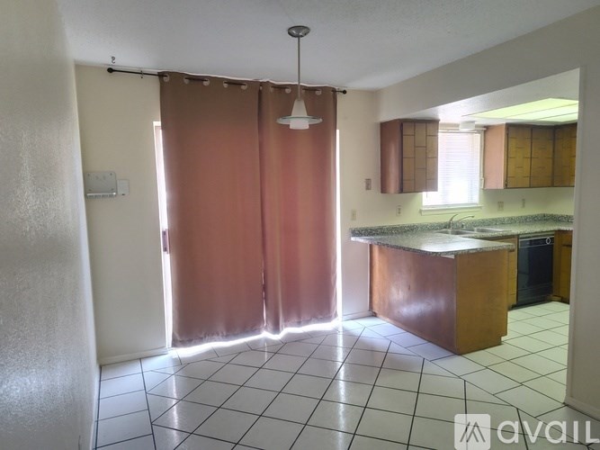 A kitchen with a brown counter and white tiled floor.