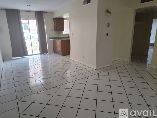 A spacious room with a kitchen area and a tiled floor.