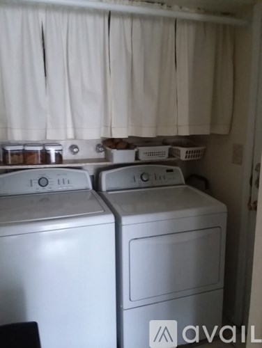 Two white front loading washing machines in a small laundry room.