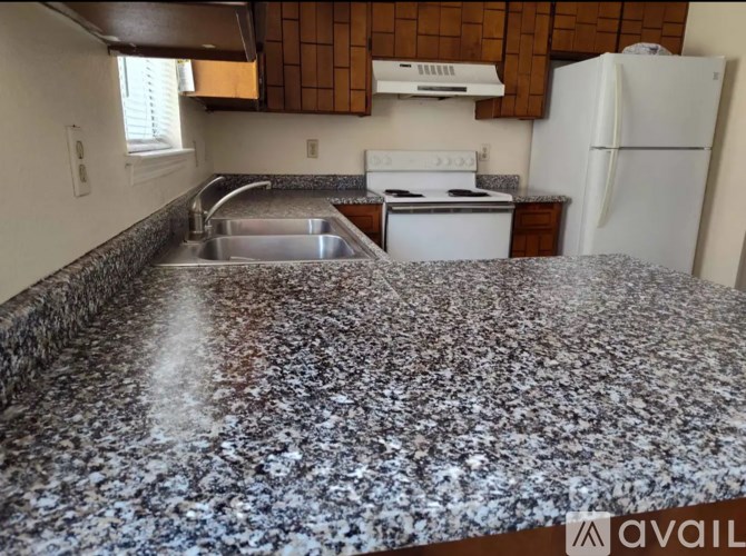 A kitchen with a granite countertop and a white fridge.