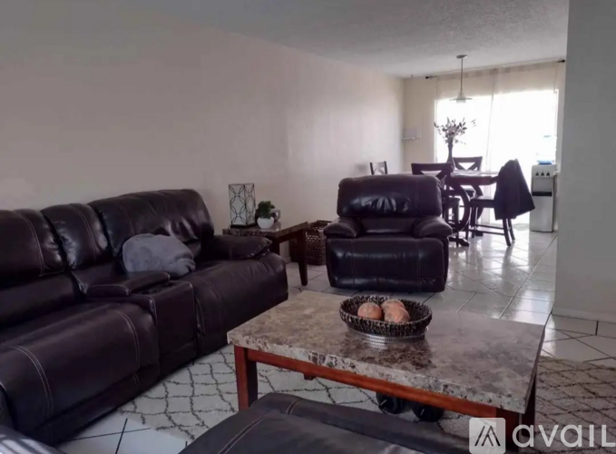 A living room with a black leather couch and a marble table.