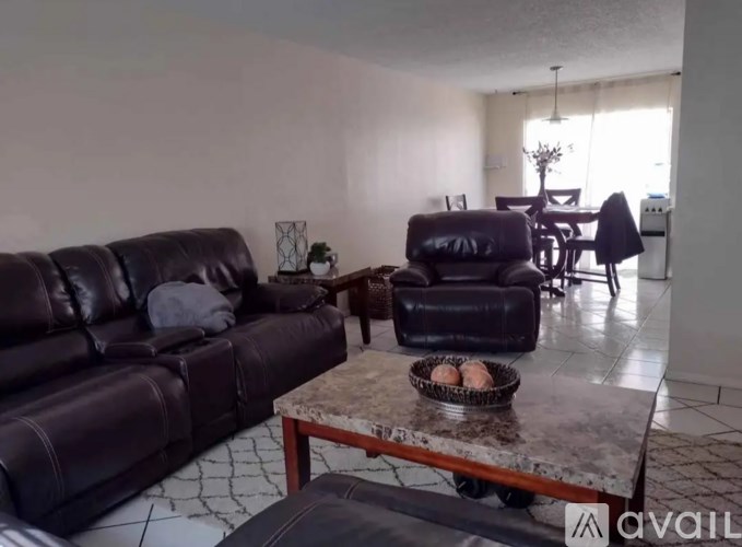 A living room with a black leather couch and a marble table.