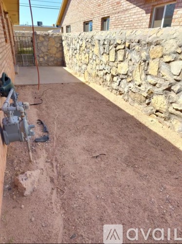 A backyard with a stone wall and a dirt ground.