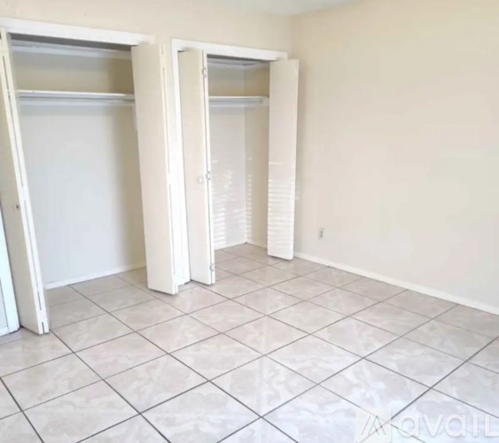 A room with white tiled floors and white closet doors.