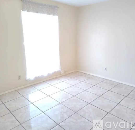 A room with white tile flooring and a window with a white frame.