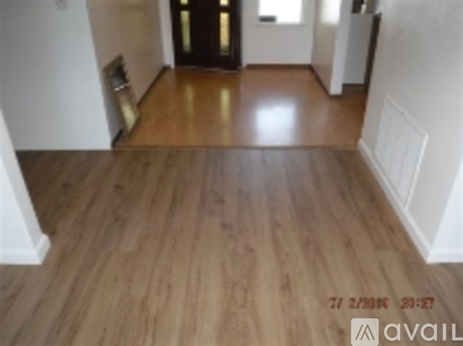 A room with wooden flooring and a white wall.