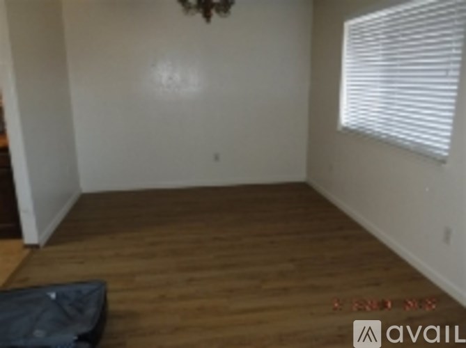 A room with wooden floors and a window with blinds.