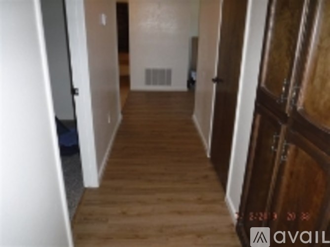 A long hallway with wood floors and white walls.