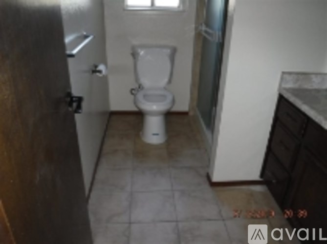 A white toilet in a small bathroom with a brown door.