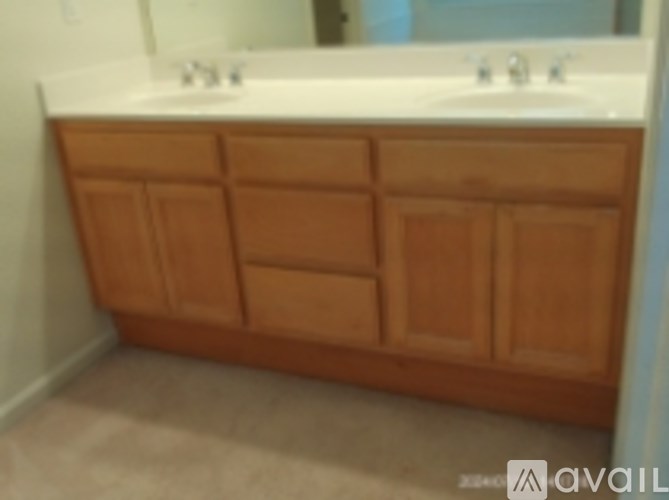 A bathroom vanity with a white counter top and brown drawers.