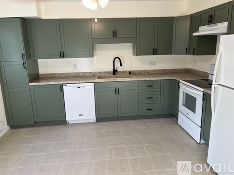 A kitchen with green cabinets and white appliances.