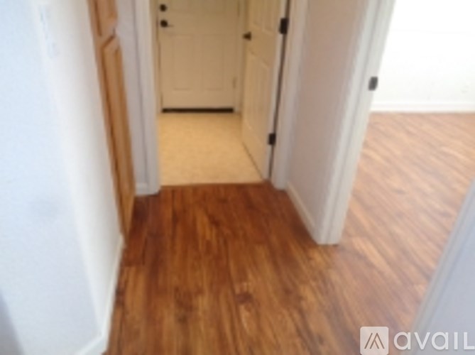 A hallway with wood floors and white walls.