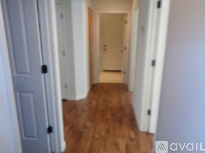 A hallway with wood floors and white walls.