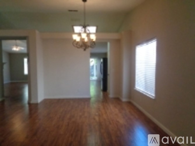 A room with wooden floors and a chandelier hanging from the ceiling.