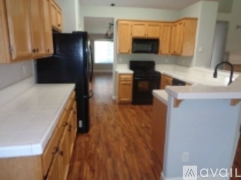 A kitchen with a black refrigerator and wooden cabinets.