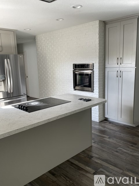 A modern kitchen with a stainless steel refrigerator, a built-in oven, and a countertop with a cutting board and knife block.