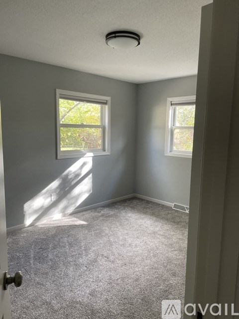 A room with a carpeted floor and two windows.