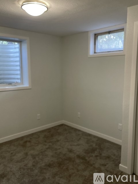 A room with a carpeted floor and a window with blinds.