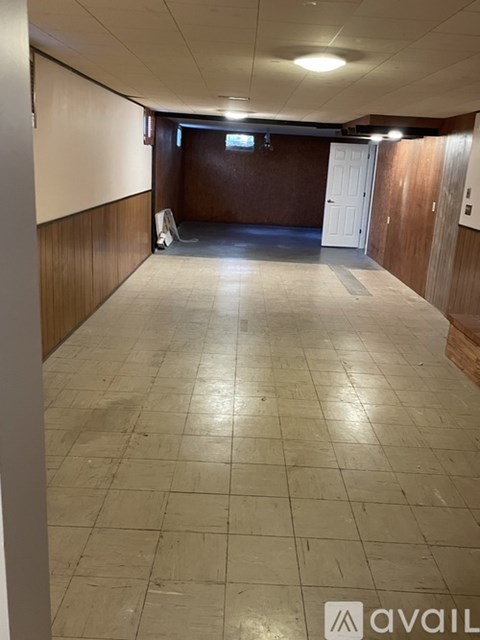 A long hallway with a white wall on the left and a brown wall on the right.