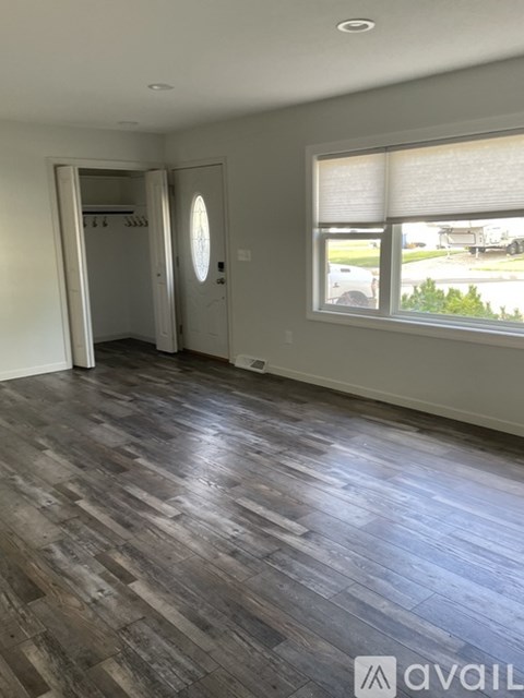 A room with wooden flooring and a window overlooking a street.