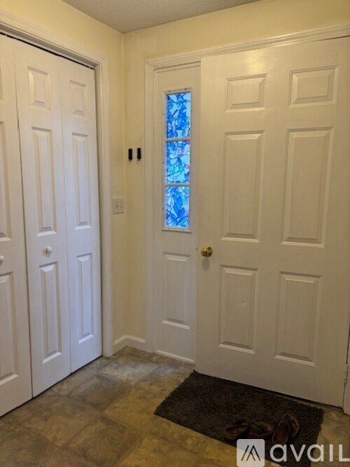 A hallway with a white door and a stained glass window.