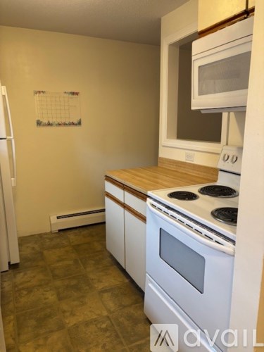 A kitchen with white appliances and a calendar on the wall.