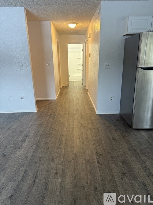 A long hallway with wood floors and white walls.