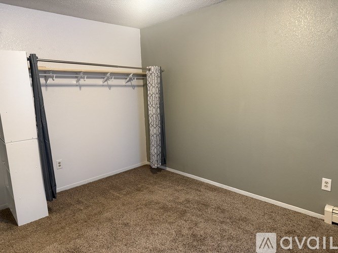 A room with a carpeted floor and a white wall with a grey headboard.