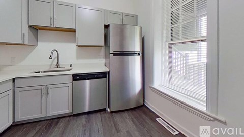A kitchen with white cabinets and a stainless steel refrigerator.