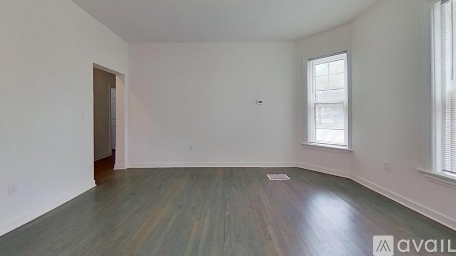 A room with wooden flooring and a window with blinds.