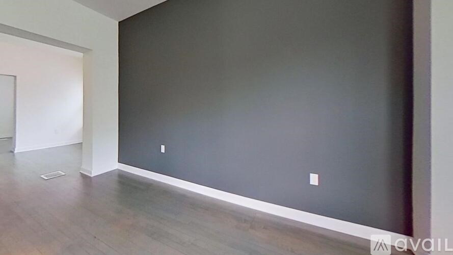 A room with a grey wall and wooden floor.