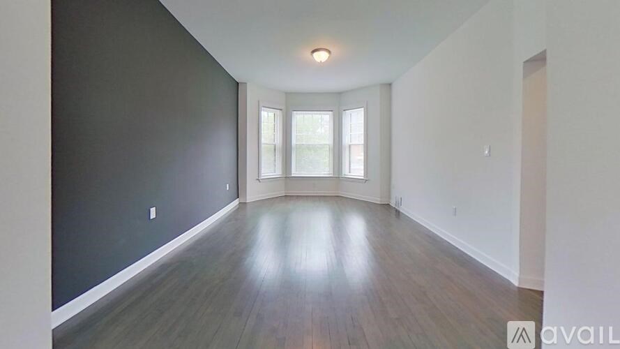 A spacious room with wooden floors and a window.