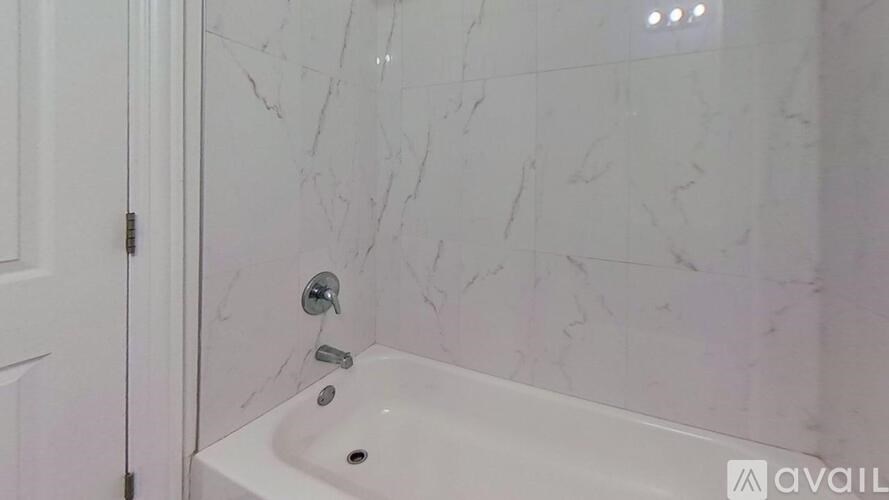 A white bathroom sink with a marble patterned wall behind it.