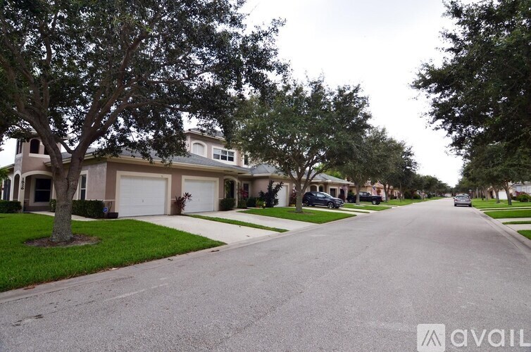 A residential street with houses on both sides and a car driving down the road.