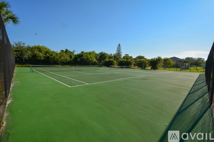 A tennis court surrounded by trees and a clear blue sky.