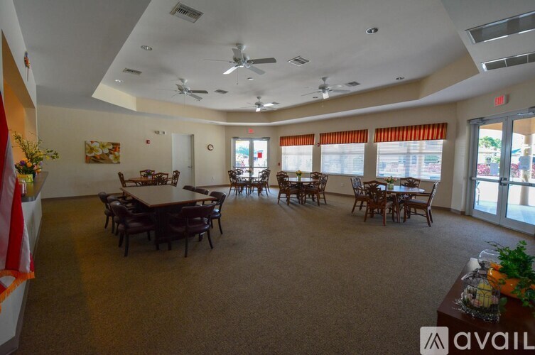 A room with a long table and chairs, a ceiling fan, and a flag on the left side.