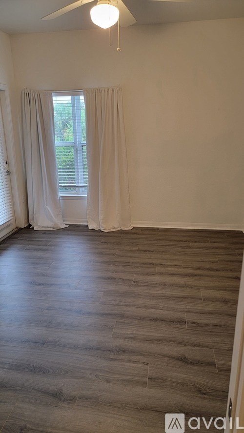 A room with wooden flooring and a window with curtains.