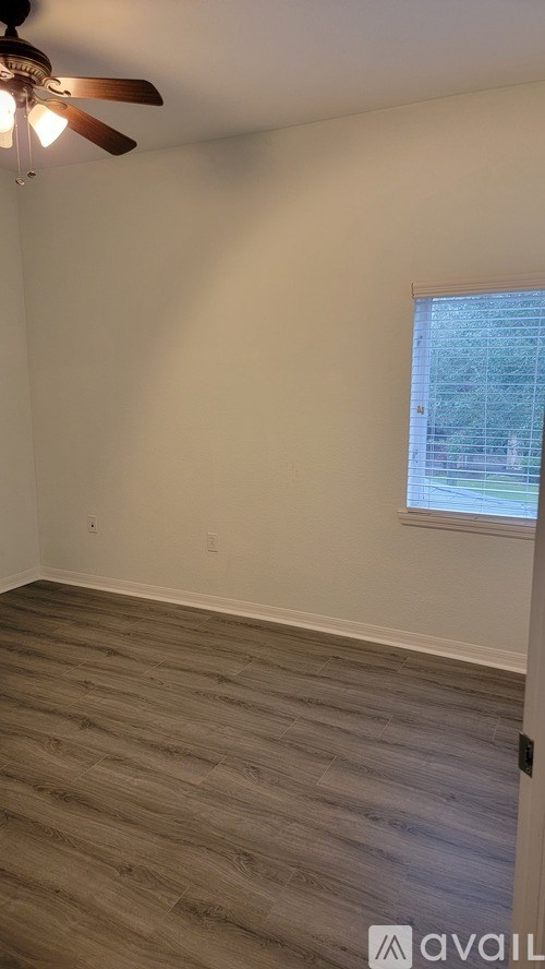 A room with a ceiling fan and a window with blinds.