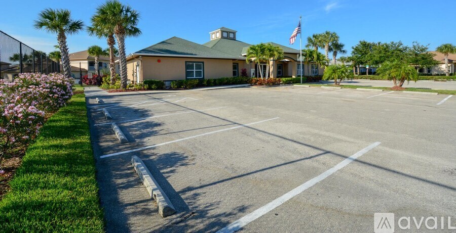 A parking lot with a building and palm trees in the background.