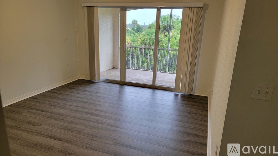 A room with wooden flooring and a sliding glass door leading to a balcony.