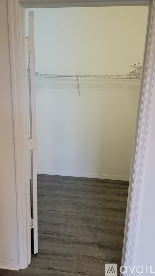A white closet with a wooden floor and a white door.