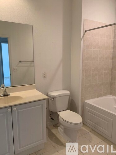 A white toilet sits in a bathroom next to a sink and a bathtub.