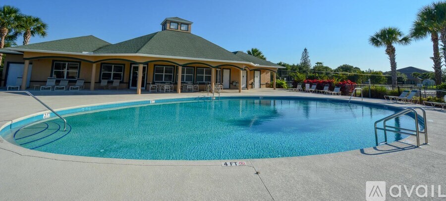 A large swimming pool with a diving board and a building with a green roof in the background.