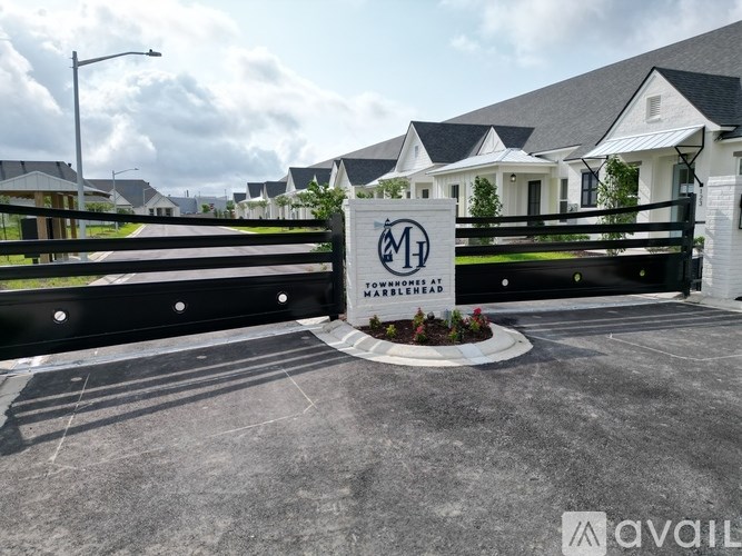 A sign with the letter M and the word "AVAILABLE" in front of a gated community.