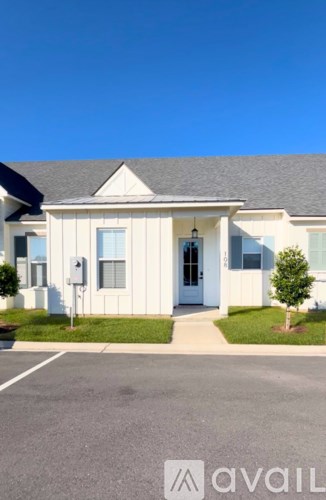 A white house with a blue door and a small tree in front.