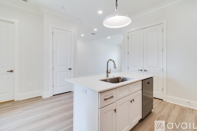 A kitchen with white cabinets and a sink under a light fixture.