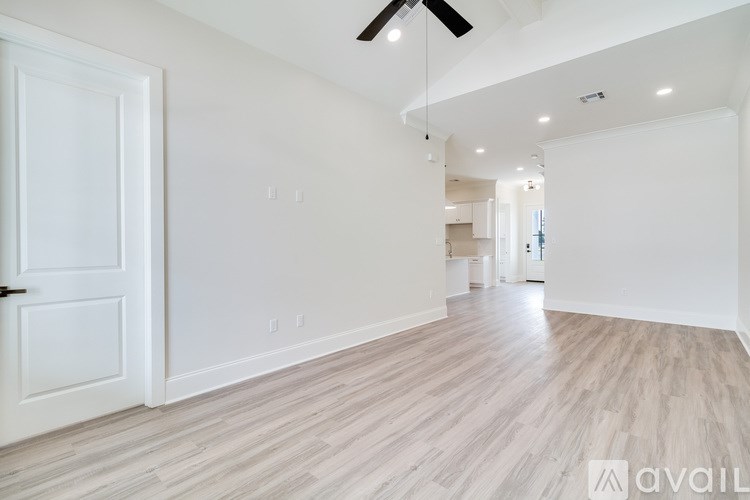 A spacious room with wooden flooring and a ceiling fan.