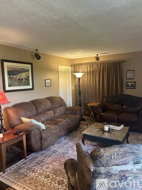 A living room with a brown couch, a coffee table, and a painting on the wall.