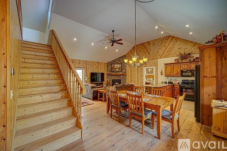A wooden staircase leads to a living room with a dining table and chairs.