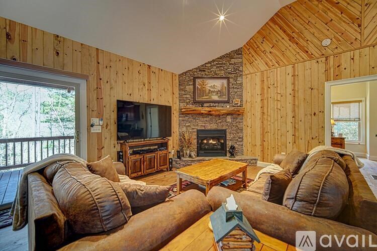 A living room with wooden walls and a fireplace.
